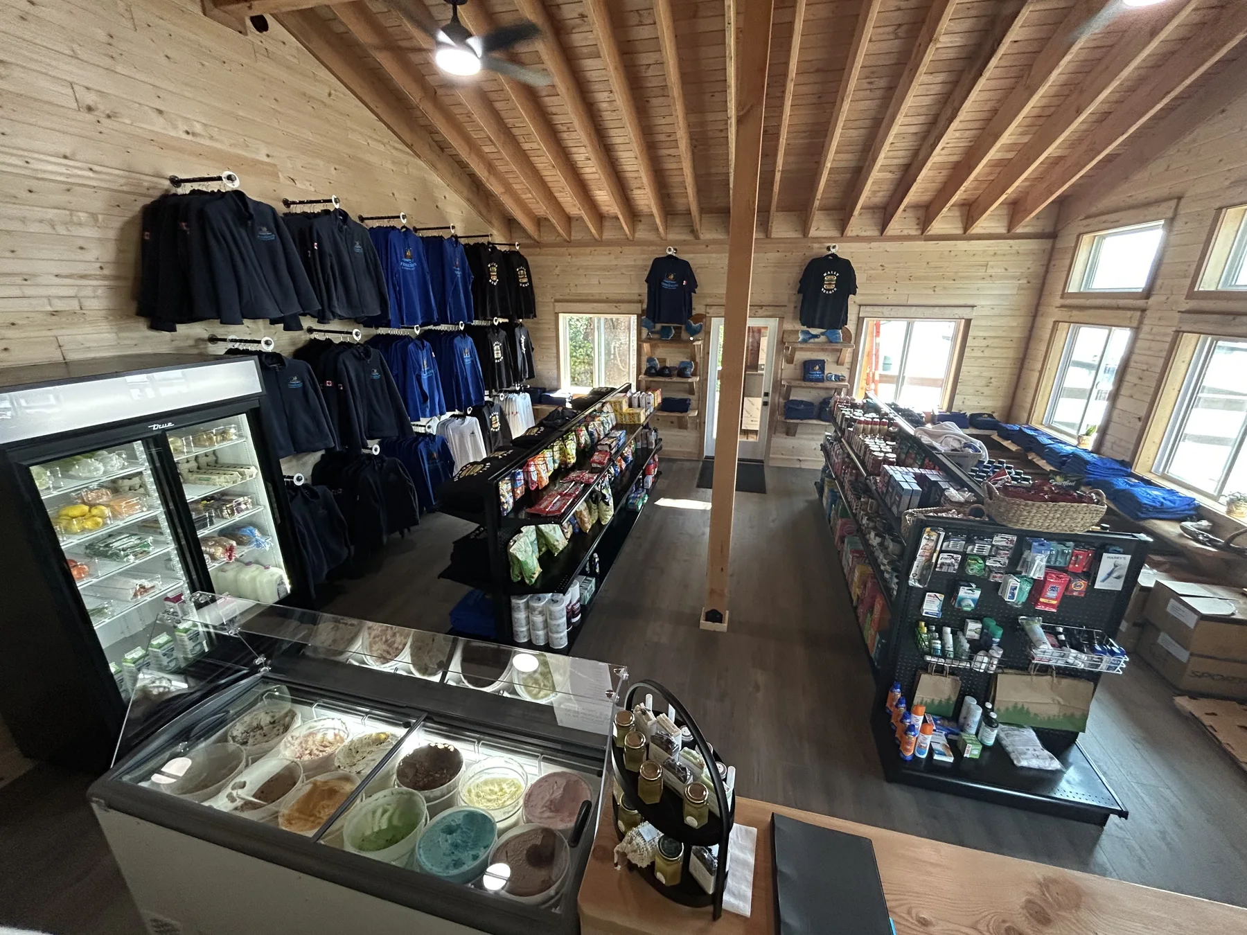 Inside the Landing Store — the ice cream counter, apparel wall, and stocked grocery aisles under the cedar ceiling
